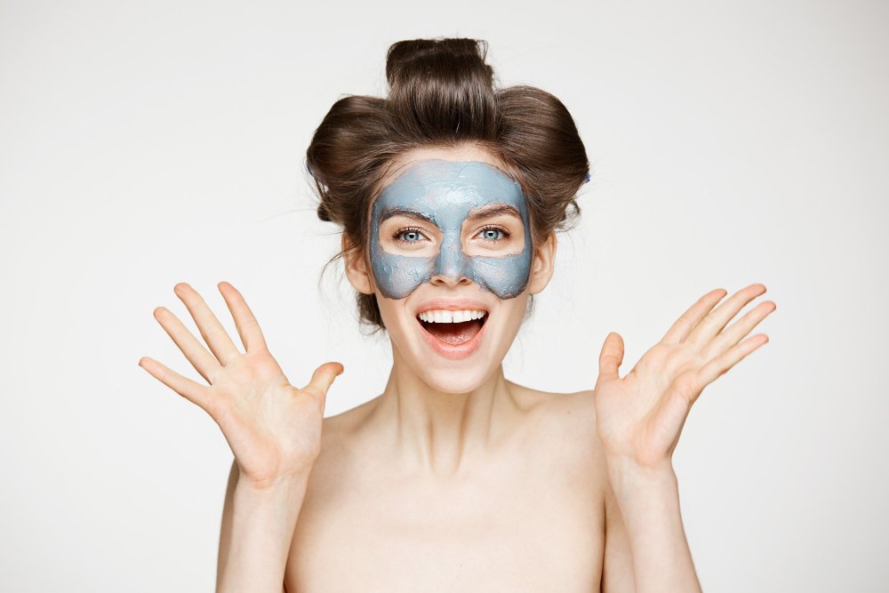 Teen girl gently applying a homemade face mask to her cheeks